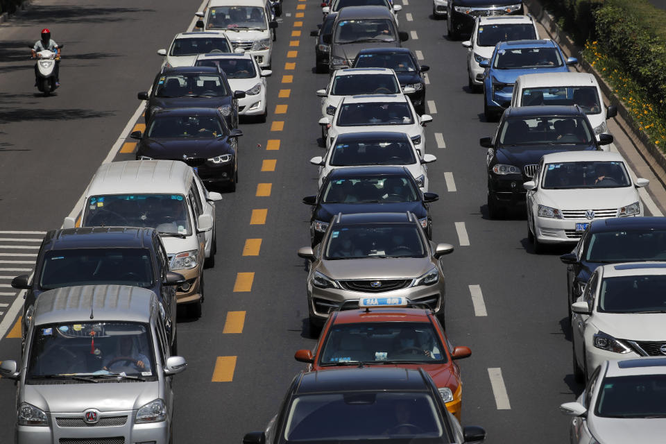 A man rides on an electric-powered scooter passes by motorists clogged with heavy traffic on a city ring road in Beijing, Tuesday, Aug. 11, 2020. China’s auto sales rose by 16.4% in July over a year earlier to 2.1 million units in a sign of sustained recovery for the industry’s biggest global market, an industry group said Tuesday.(AP Photo/Andy Wong)