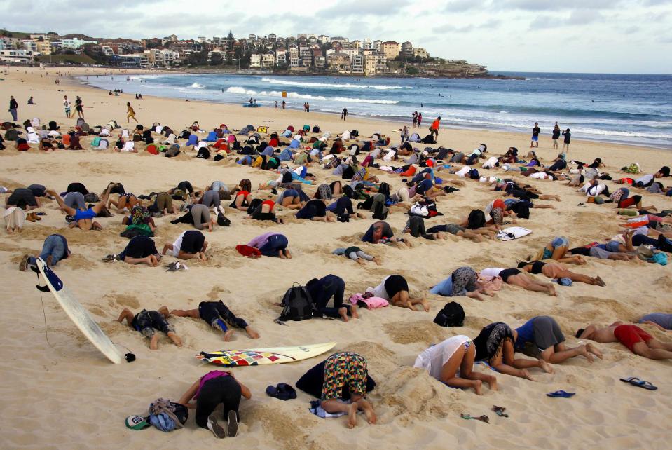 A group of around 400 demonstrators participate in a protest by burying their heads in the sand at Sydney's Bondi Beach November 13, 2014. Hundreds of protesters participated in the event, held ahead of Saturday's G20 Leader's Summit in Brisbane, which was being promoted as a message to Australian Prime Minister Tony Abbott�s government that, "You have your head in the sand on climate change". REUTERS/David Gray (AUSTRALIA - Tags: POLITICS CIVIL UNREST SOCIETY ENVIRONMENT)