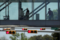 A man has his temperature taken at a control point on a covered footbridge to be screened for symptoms before entering the Dell Deton Medical Center at the University of Texas in Austin, Texas, Wednesday, March 25, 2020. Austin is under Stay-at-Home orders to help battle the effects of COVID-19. (AP Photo/Eric Gay)