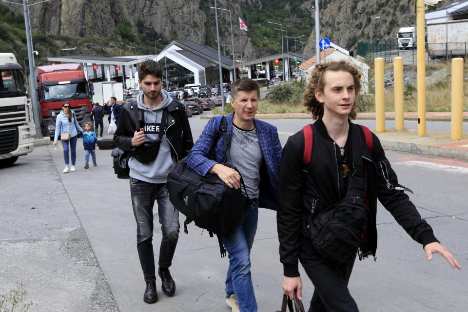 FILE A group of young Russians walk along the border crossing Verkhny Lars between Georgia and Russia on Friday, Sept. 23, 2022. Long lines of vehicles have formed at a border crossing between Russia's North Ossetia region and Georgia after Moscow announced a partial military mobilization. A day after President Vladimir Putin ordered a partial mobilization to bolster his troops in Ukraine, many Russians are leaving their homes. (AP Photo/Shakh Aivazov, File)