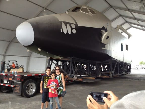 An unidentified family poses for a photo with the original space shuttle mockup after it was moved to a tent outside the Columbia Memorial Space Center in Downey, Calif., July 12, 2012.