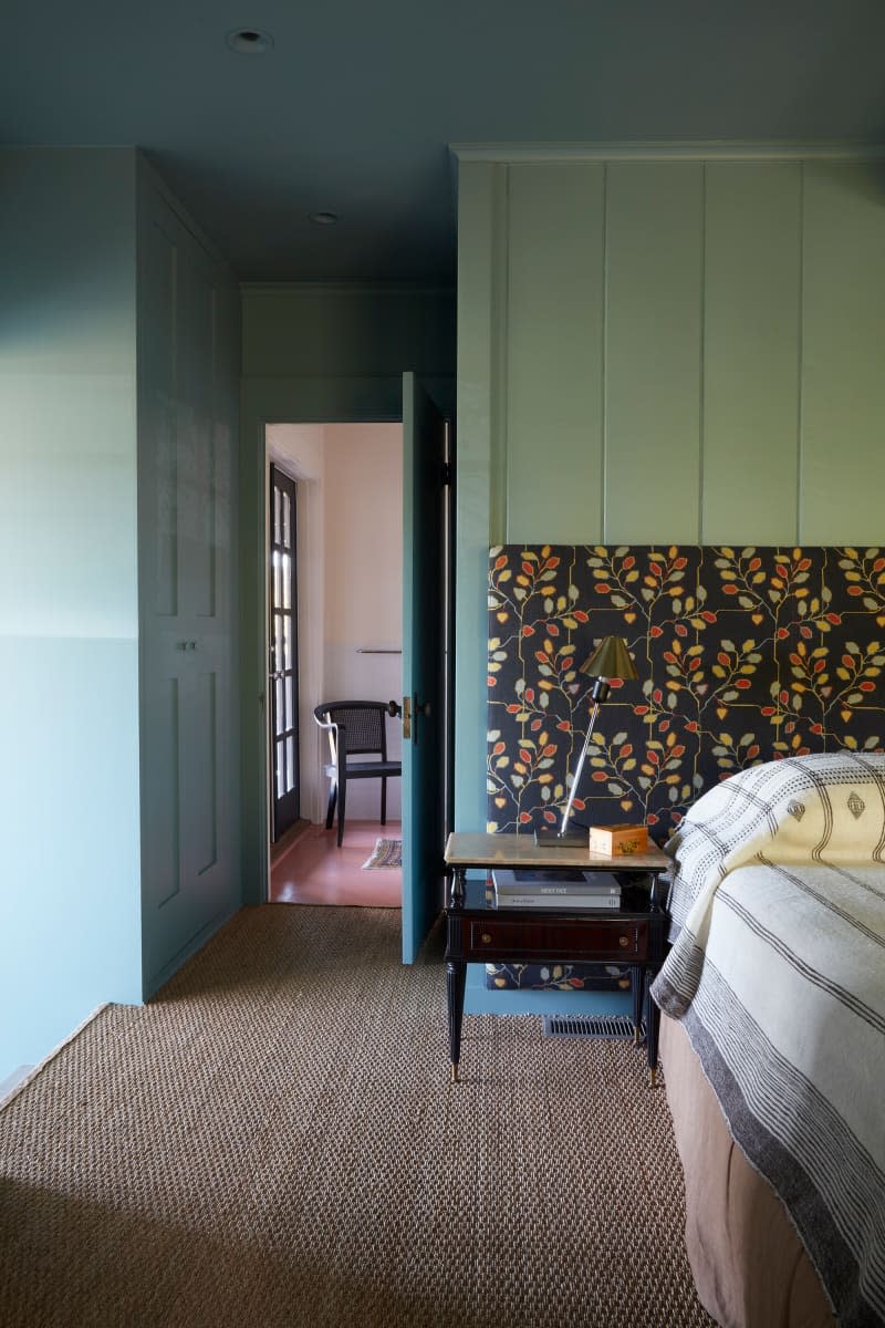 Green painted wood paneled walls in bedroom.