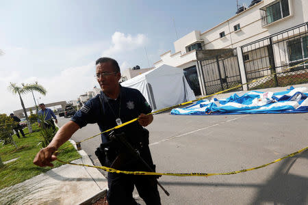 A police officer cordons off a crime scene outside of a house where eleven people were found dead at Villa de los Milagros residential park, in the city of Tizayuca in Mexican state of Hidalgo, Mexico, July 13, 2017. REUTERS/Edgard Garrido