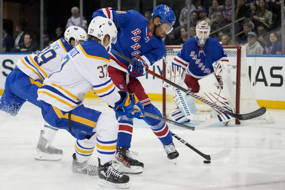 New York Rangers defenseman K'Andre Miller, center, battles for the puck against Buffalo Sabres center Casey Mittelstadt (37) during the second period of an NHL hockey game, Monday, April 10, 2023, in New York. (AP Photo/John Minchillo)