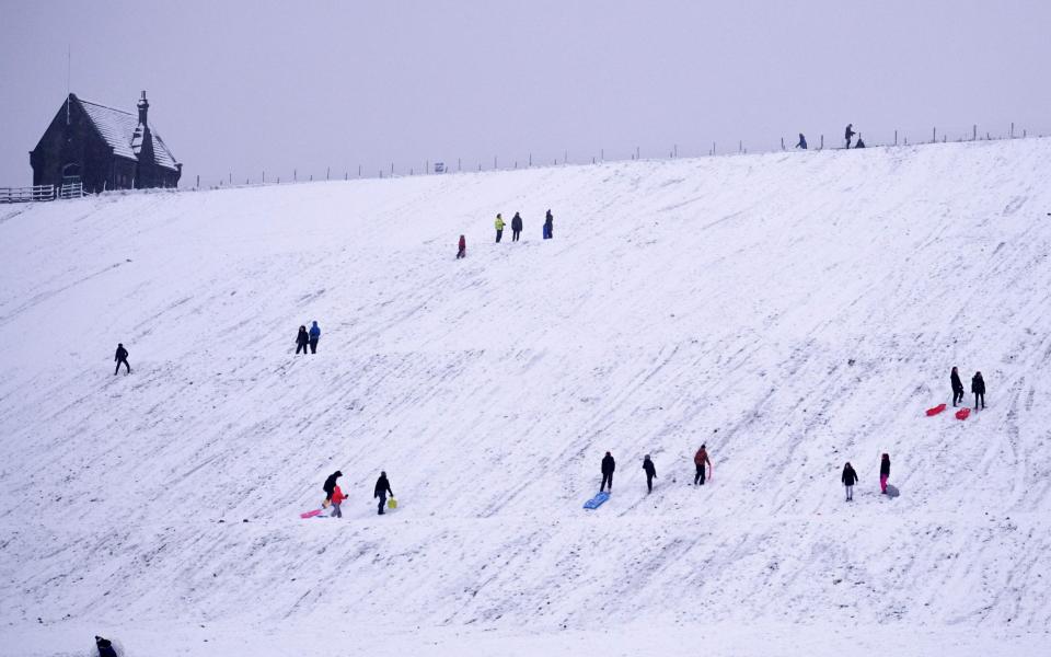 People sledge down a hillside at Butterley Reservoir in Marsden, northern England - AFP