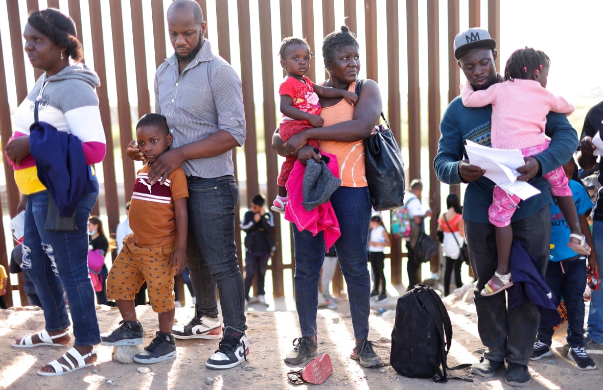 Immigrants from Haiti, who crossed through a gap in the U.S.-Mexico border barrier, wait in line to be processed by the U.S. Border Patrol on May 20, 2022 in Yuma, Arizona. Title 42, the controversial pandemic-era border policy enacted by former President Trump, which cites COVID-19 as the reason to rapidly expel asylum seekers at the U.S. border, was set to officially expire on May 23rd. A federal judge in Louisiana delivered a ruling today blocking the Biden administration from lifting Title 42. (Photo by Mario Tama/Getty Images)