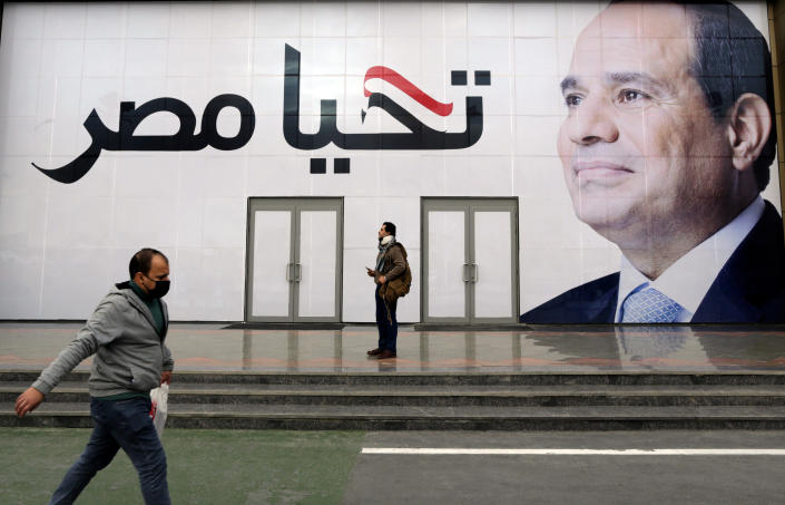 A man walks in front of a billboard for Egyptian President Egyptian President Abdel-Fattah el-Sissi, with Arabic that reads, Long live Egypt, at the annual Cairo International Book Fair, in Cairo, Egypt, Thursday, Jan. 27, 2022. Publishers from 51 countries participate in the 53rd edition of the Cairo International Book Fair from January 26 to February 7, General Egyptian Book Organization said. (AP Photo/Amr Nabil)