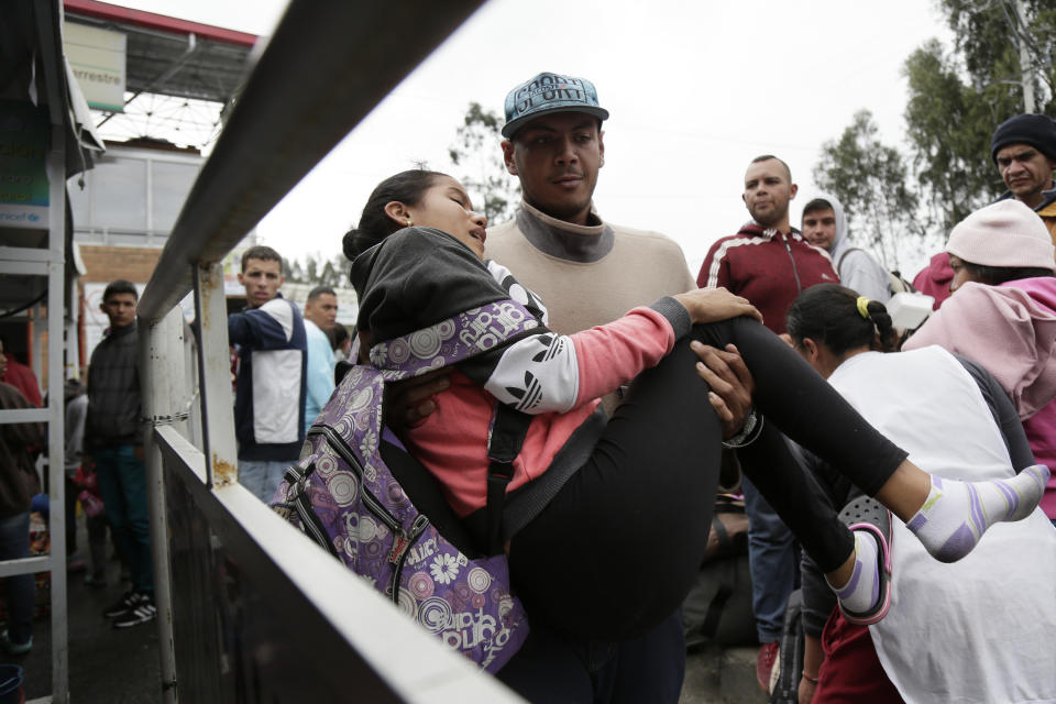 A woman who collapsed is carried by her husband, on the Rumichaca bridge, before crossing the border from Colombia to Ecuador, Thursday, June 13, 2019. Venezuelan migrants are making their way to Peru, where on June 15, the country will start requiring them to have a passport and a humanitarian visa. (AP Photo/Dolores Ochoa)