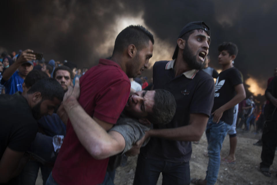 Palestinian protesters evacuate a wounded man was shot by Israeli troops during a protest at the Gaza Strip's border with Israel, Friday, Oct. 12, 2018. (AP Photo/Khalil Hamra)