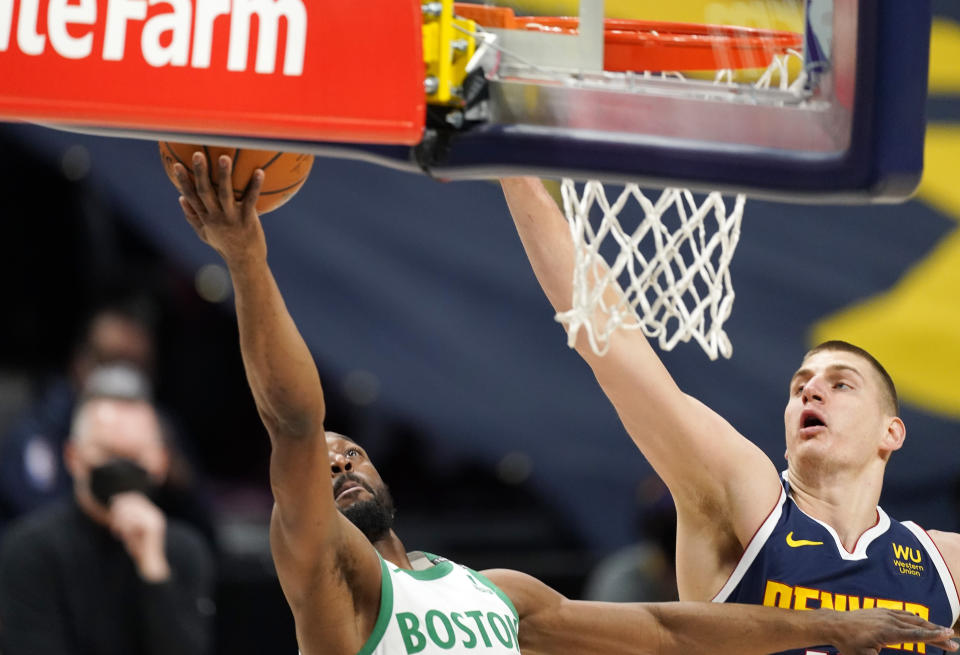 Boston Celtics guard Kemba Walker, left, drives to the rim as Denver Nuggets center Nikola Jokic, right, defends in the first half of an NBA basketball game Sunday, April 11, 2021, in Denver. (AP Photo/David Zalubowski)