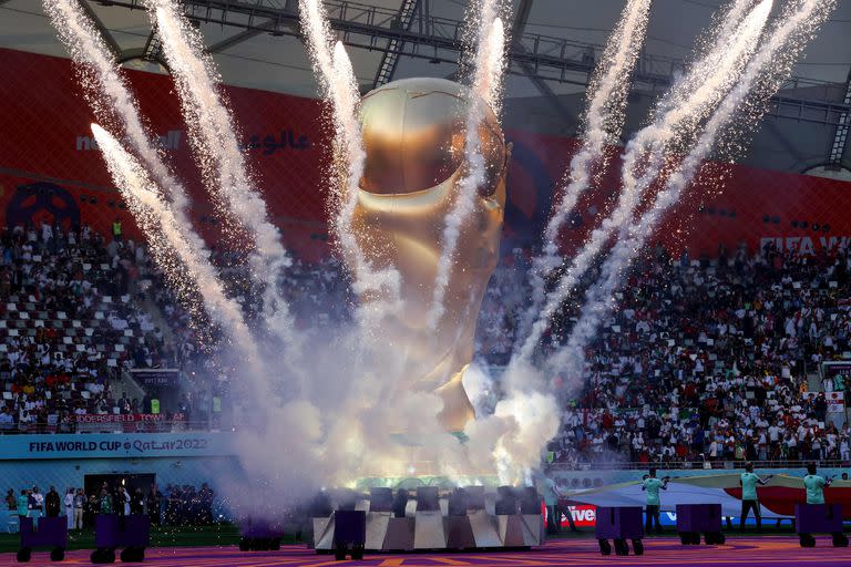 Los fuegos artificiales explotan alrededor de una réplica gigante del trofeo de la Copa Mundial de la FIFA, antes del inicio del partido entre Inglaterra e Irán en el Estadio Internacional Khalifa en Doha el 21 de noviembre de 2022.