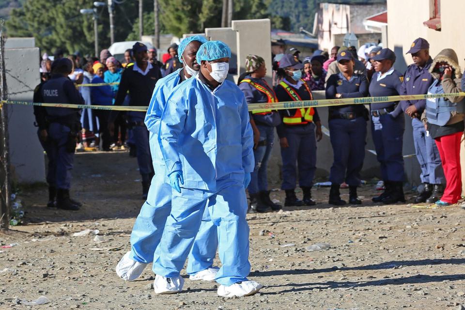 Forensic experts work outside a tavern for the death of teenagers in East London, South Africa