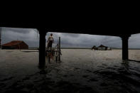 A man stands in front of his house during high tides in Sriwulan village in Demak, Indonesia, January 30, 2018. REUTERS/Beawiharta