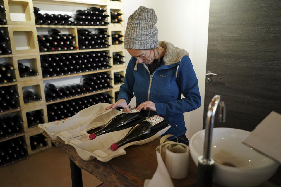 In this photo taken on Wednesday, Nov. 13, 2019, winemaker Claire Chasselay lays the labels on bottles of wine s in her cellar in Chatillon d'Azergues, in the Beaujolais region, eastern France. Celebration is the mot du jour in France’s Beaujolais region on the third Thursday of November, when winemakers and sellers uncork the season’s Beaujolais Nouveau with feasting and fanfare. (AP Photo/Laurent Cipriani)