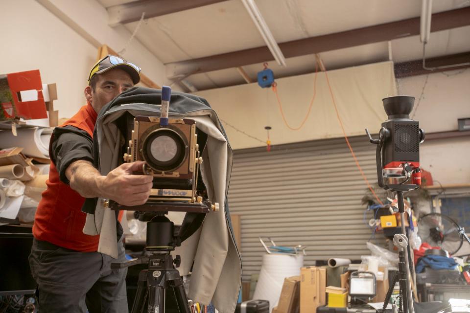 Wilson peeks out from the side of his large-format view camera as he reaches to adjust the lens.