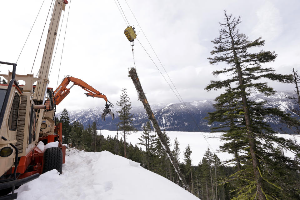 In this Feb. 22, 2017, photo, a log yarder hauls a log up a steep slope where a crew is thinning a 100-acre patch on private land owned by the Nature Conservancy overlooking Cle Elum Lake, in Cle Elum, Wash. As part of a broader plan by the nonprofit environmental group to restore the pine forests of the Central Cascades so they are more resilient to wildfires and climate change, they're cutting down trees to save the forest. (AP Photo/Elaine Thompson)