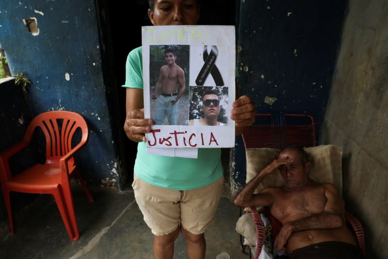 Judith Cortez sostiene fotos de sus hijos José Alfredo y Anderson Torres con la escritura "El Tocuyo en duelo" y "Justicia", mientras su esposo Rómulo descansa en su casa, en El Tocuyo, Venezuela, el 18 de septiembre de 2019