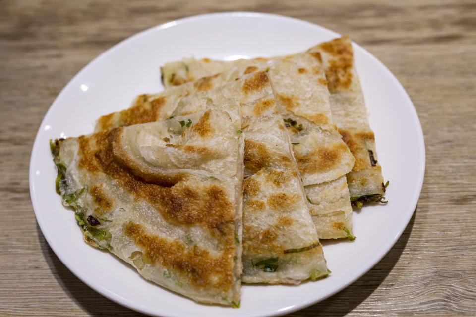 A plate of scallion pancakes sliced into triangles.