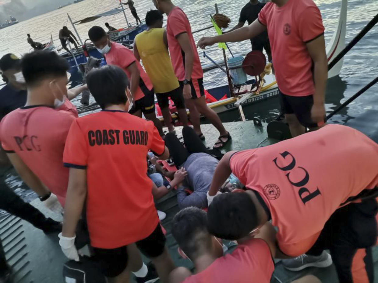 In this handout photo provided by the Philippine Coast Guard, rescuers assist a passenger of the M/V Asia Philippines, an inter-island cargo and passenger vessel, as it caught fire while approaching Batangas port, southern Philippines on Friday Aug. 26, 2022. A Philippine ferry carrying 82 passengers and crew caught fire as it was approaching a port south of Manila on Friday. coast guard officials said. Most of the passengers and crew have been rescued as search operations continue for others missing. (Philippine Coast Guard via AP)