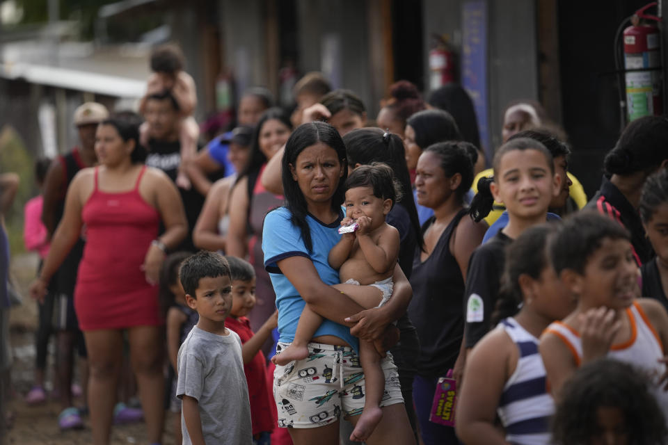 Venezuelan migrant Minorca Parra holds her daughter Karin Alvear as she lines up to receive food in a temporary camp after crossing the Darien Gap from Colombia in Lajas Blancas, Panama, Thursday, June 27, 2024. (AP Photo/Matias Delacroix)