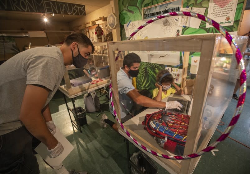 Kindergartner Jameson Miniex, 5, works with facilitator Kyle Fetter, left, and Star Education Director John Gaxiola inside his protective, learning pod at Eco Station in Culver City. <span class="copyright">(Mel Melcon / Los Angeles Times)</span>