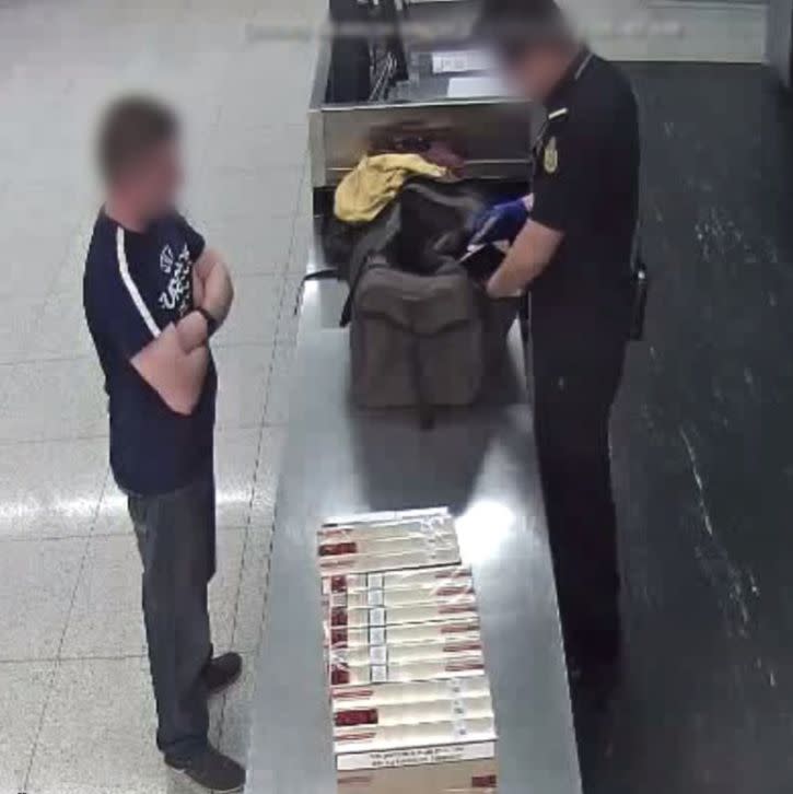 An officer pictured inspecting a cigarette smuggler's bag at Perth Airport. 