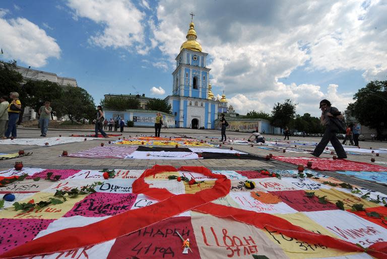 People walk past quilts on Mikhaylovskaya Square in Kiev on May 13, 2011 to commemorate AIDS victims in Ukraine