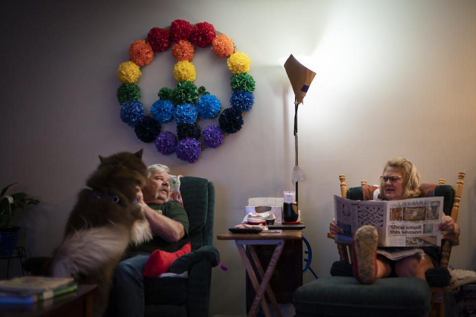 Jimmy and Susan Ryder spend their evening reading the paper and playing with their dog, Captain, when they finally have the evening to themselves after Susan's mother has gone to bed, Monday, Nov. 29, 2021, in Rotterdam Junction, N.Y. (AP Photo/Wong Maye-E)