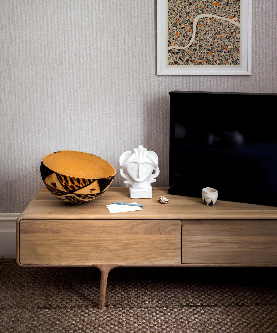 Close up of low wooden sideboard decorated with ornaments, TV placed to the side