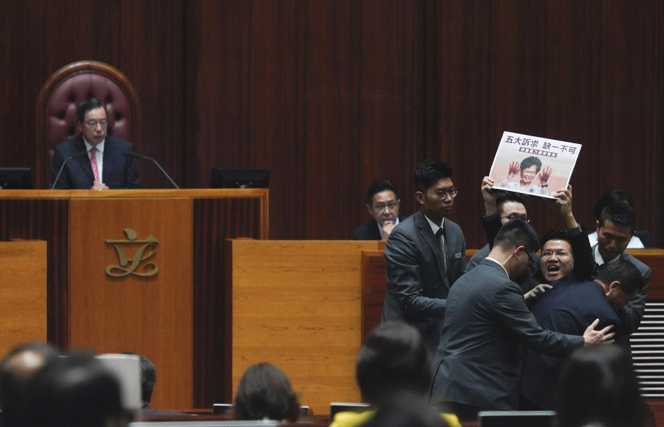 Pro-democracy lawmaker Gray Fan, second from right, is taken away as he shouts a slogan while Hong Kong Chief Executive Carrie Lam arrives at chamber of the Legislative Council in Hong Kong, on Thursday, Oct. 17, 2019. (AP Photo/Vincent Yu)