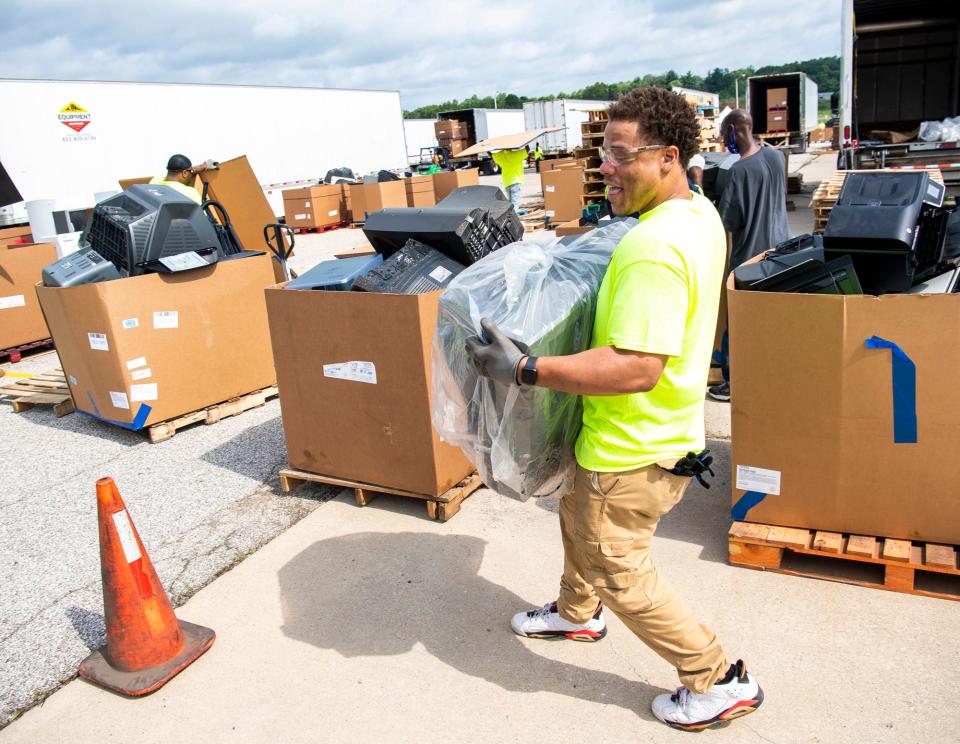 Big Boy Moving Services' Nas Buie carries a discarded television to a cardboard bin Saturday during the 2021 Community Electronic Recycling Day at the Cook Profile Park facility.