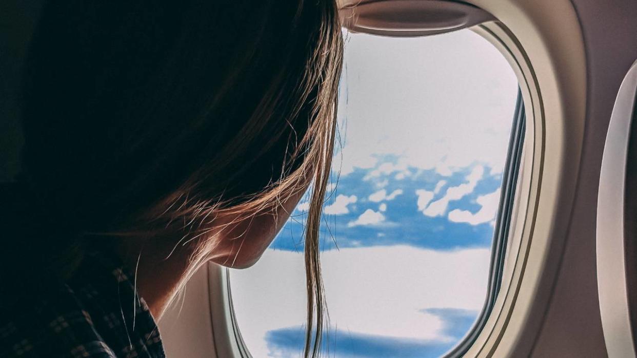  Travel gadgets, woman looking out from a plane window 