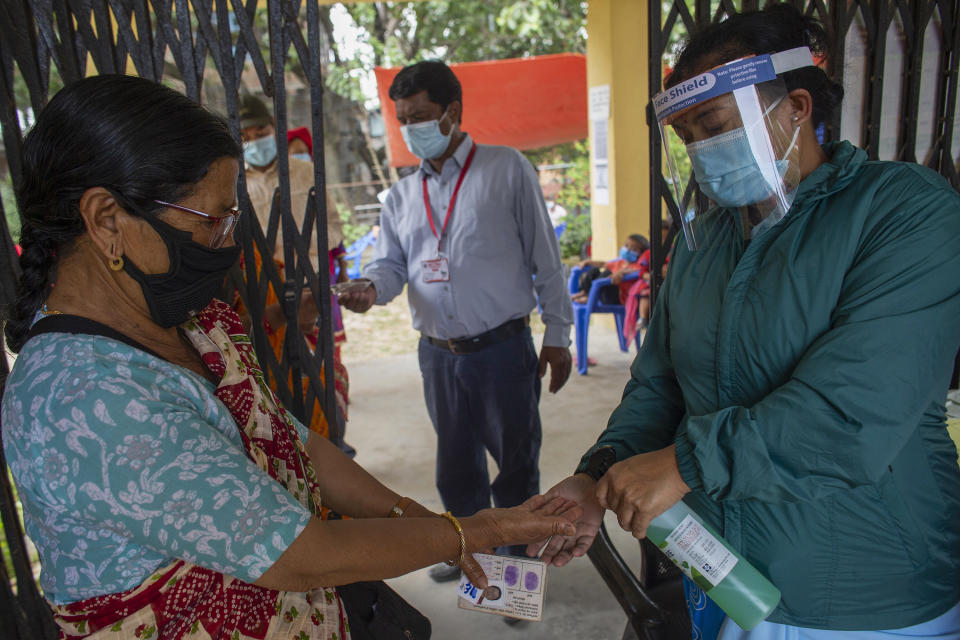 A Nepalese health worker sanitizes the hands of a woman as she arrives gets inoculated against the coronavirus in Kathmandu, Nepal, Tuesday, June 8, 2021. Nepal resumed its stalled coronavirus vaccination campaign on Tuesday with 1 million doses given by China after the Himalayan nation made international pleas for help with a shortage of doses. (AP Photos/Bikram Rai)