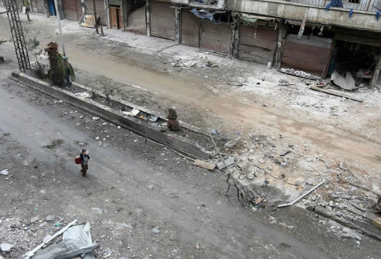 A Syrian child walks past debris in Eastern Ghouta on February 22, 2018