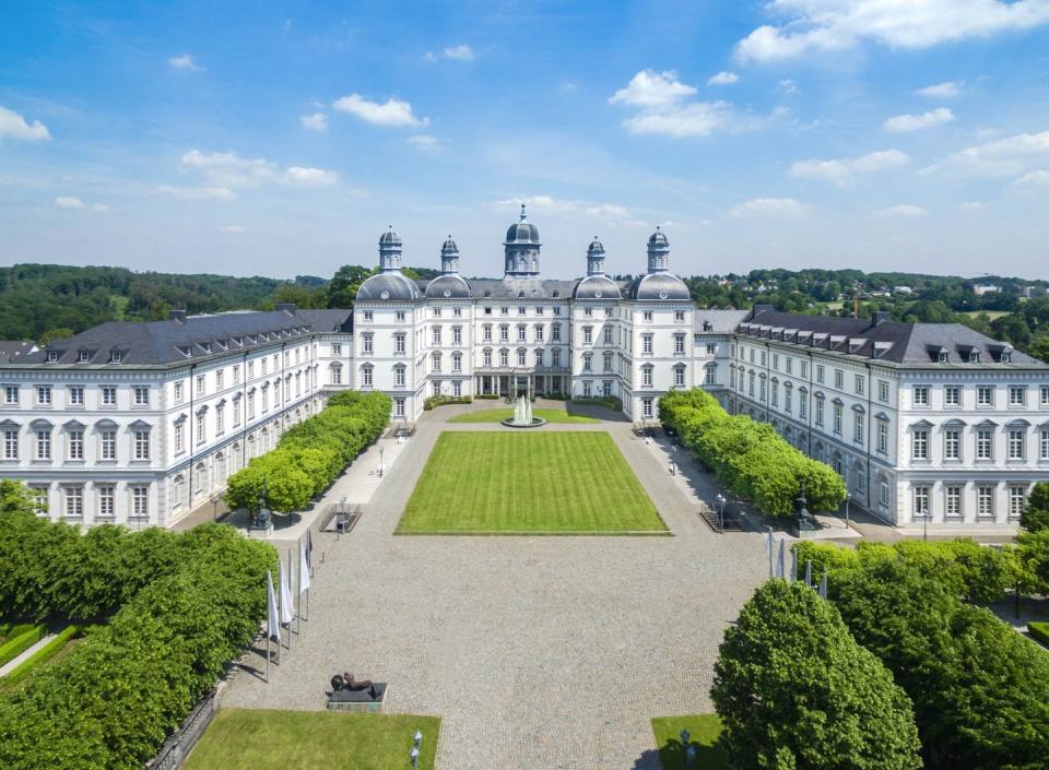 a large white building with a green lawn and trees in front of it