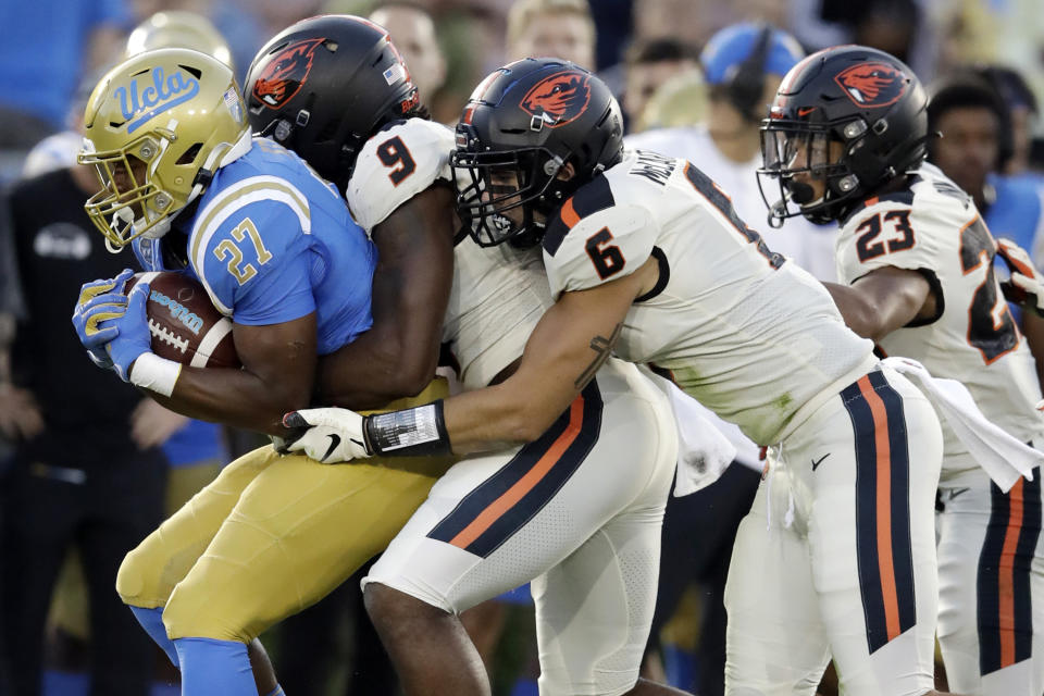 FILE - In this Oct. 5, 2019, file photo, UCLA running back Joshua Kelley, left, is tackled by Oregon State linebackers Hamilcar Rashed Jr. (9) and John McCartan (6) during the first half of an NCAA college football game in Pasadena, Calif. While the offense is still coming together with presumed starting quarterback Tristan Gebbia, it's Oregon State's defense that should worry opponents. (AP Photo/Marcio Jose Sanchez, File)