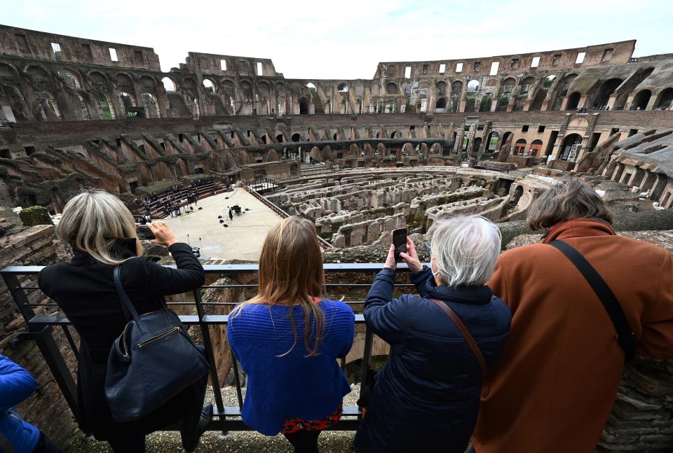 visitors take pictures as singers and musicians from the Santa Cecilia academy perform on February 1, 2021 at Rome's landmark Colosseum as it reopens amid an easing of coronavirus restrictions, with all but five Italian regions put in the low-risk "yellow" category from today. (Photo by Vincenzo PINTO / AFP) (Photo by VINCENZO PINTO/AFP via Getty Images)