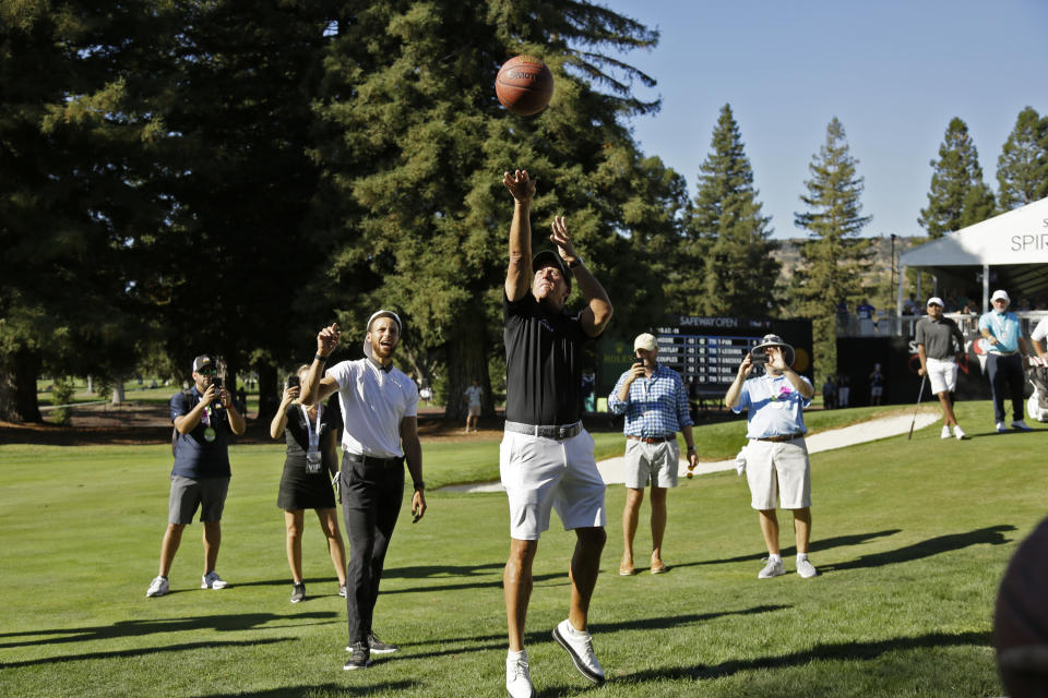 Phil Mickelson shoots a basketball below the 17th green of the Silverado Resort North Course as Stephen Curry looks on during the pro-am at the Safeway Open PGA golf tournament Wednesday, Sept. 25, 2019, in Napa, Calif. (AP Photo/Eric Risberg)