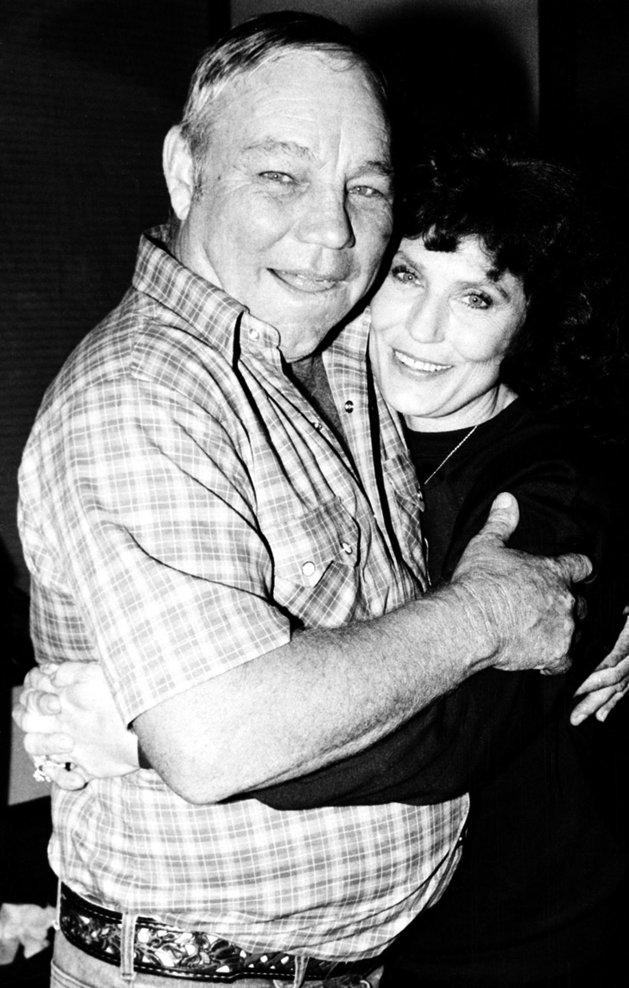Country music singer Loretta Lynn gets a hug from her husband, Oliver "Mooney" Lynn, during rehearsal for her New York debut, Thursday, Oct. 21, 1982.  Lynn will perform at the Majestic Theatre for the benefit of the National Committee for the Prevention of Child Abuse.  (AP Photo/Antonio Carozza)