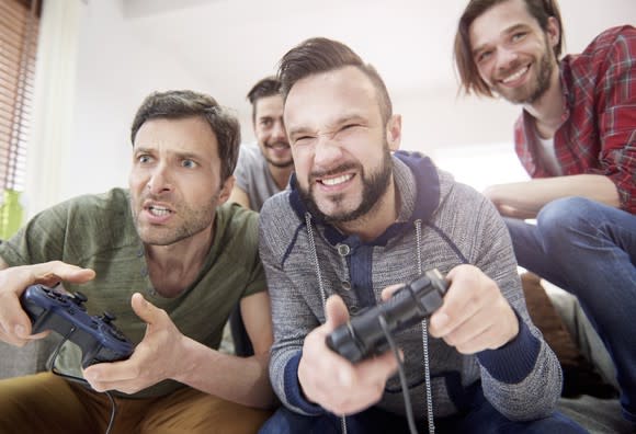 Four young men sitting on a couch playing video games.