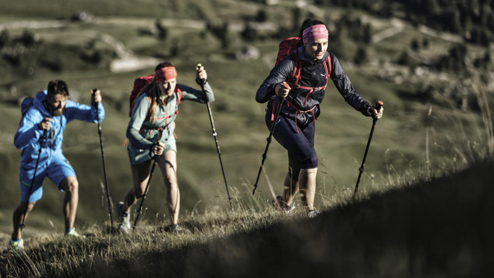 Three people hiking in boots with trekking poles