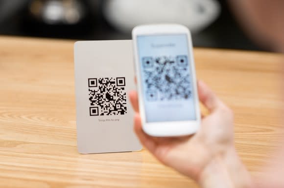 Hand holding a smartphone scanning a QR code.