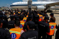 Chinese nationals (in orange vests) who were arrested over a suspected internet scam, are escorted by Chinese police officers before they were deported at Phnom Penh International Airport, in Phnom Penh, Cambodia, October 12, 2017. REUTERS/Samrang Pring