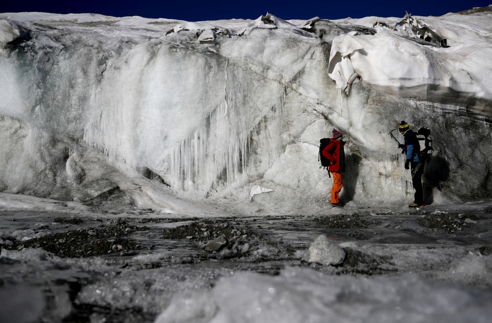 Glaciologist Andrea Fischer and environmental physicist Pascal Bohleber from the Austrian Institute for Interdisciplinary Mountain Research, inspect the thickness difference of the part of Schaufelferner glacier that is covered with a special fleece fabric protecting ice from sun and heat and the part that is not covered, near Neustift im Stubaital, Austria. (Photo: Lisi Niesner/Reuters)