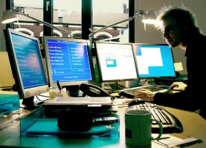 Man working with four PC screens