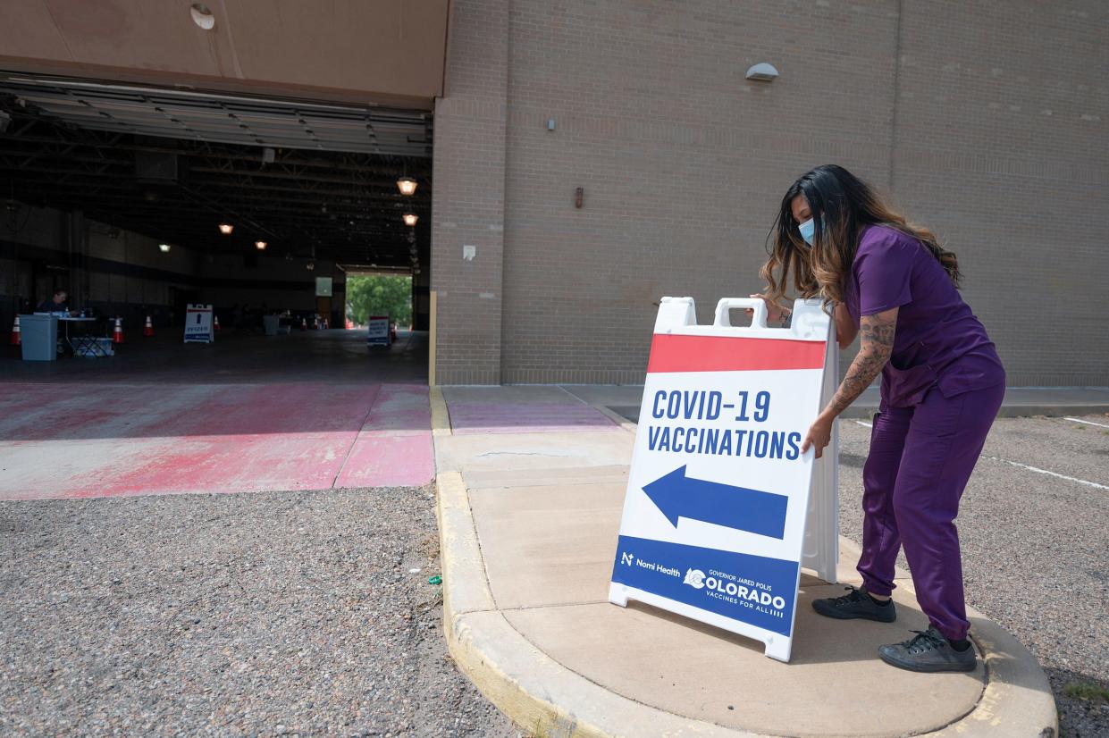 Annamarie Sabatella places a sign directing drivers to the COVID-19 mobile vaccination site at the Pueblo Mall last month.