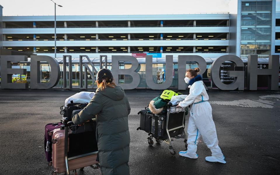 Two people wheel suitcases towards Edinburgh airport - Getty