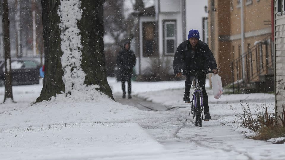 A cyclist rides on a snow-covered sidewalk on Wednesday, April 3, 2024, in Green Bay, Wisconsin. - Tork Mason/USA Today Network