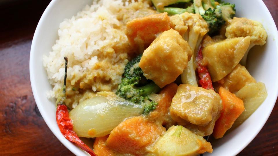 a shallow bowl of sticky white rice and sweet potato curry with cauliflower and broccoli and tofu puffs