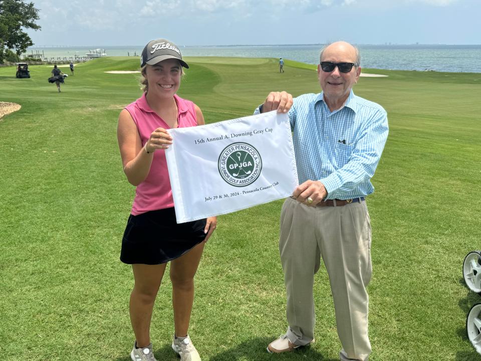 Anna Kunkel (izquierda), de Northview, recibe la bandera del campeonato de la 15.ª Copa A. Downing Gray anual en el Pensacola Country Club de manos del homónimo del torneo y legendario golfista A. Downing Gray (derecha), el martes 30 de julio de 2024.